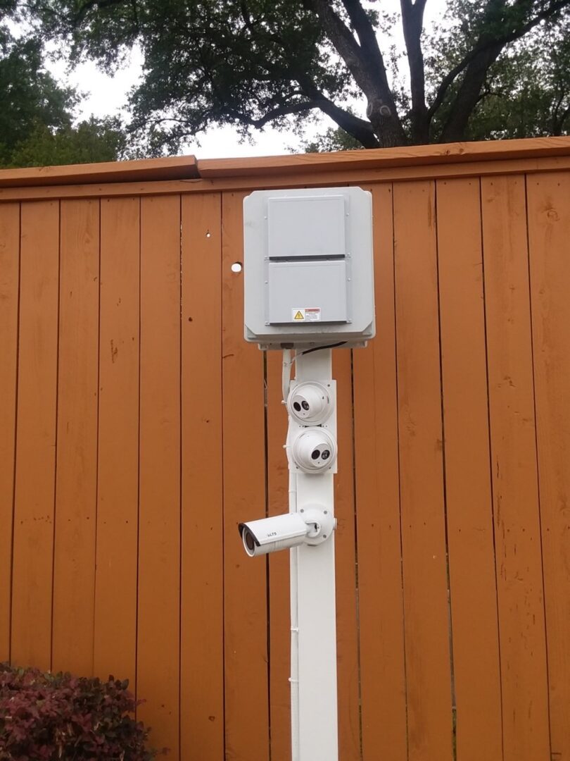 A camera mounted to the side of a wooden fence.