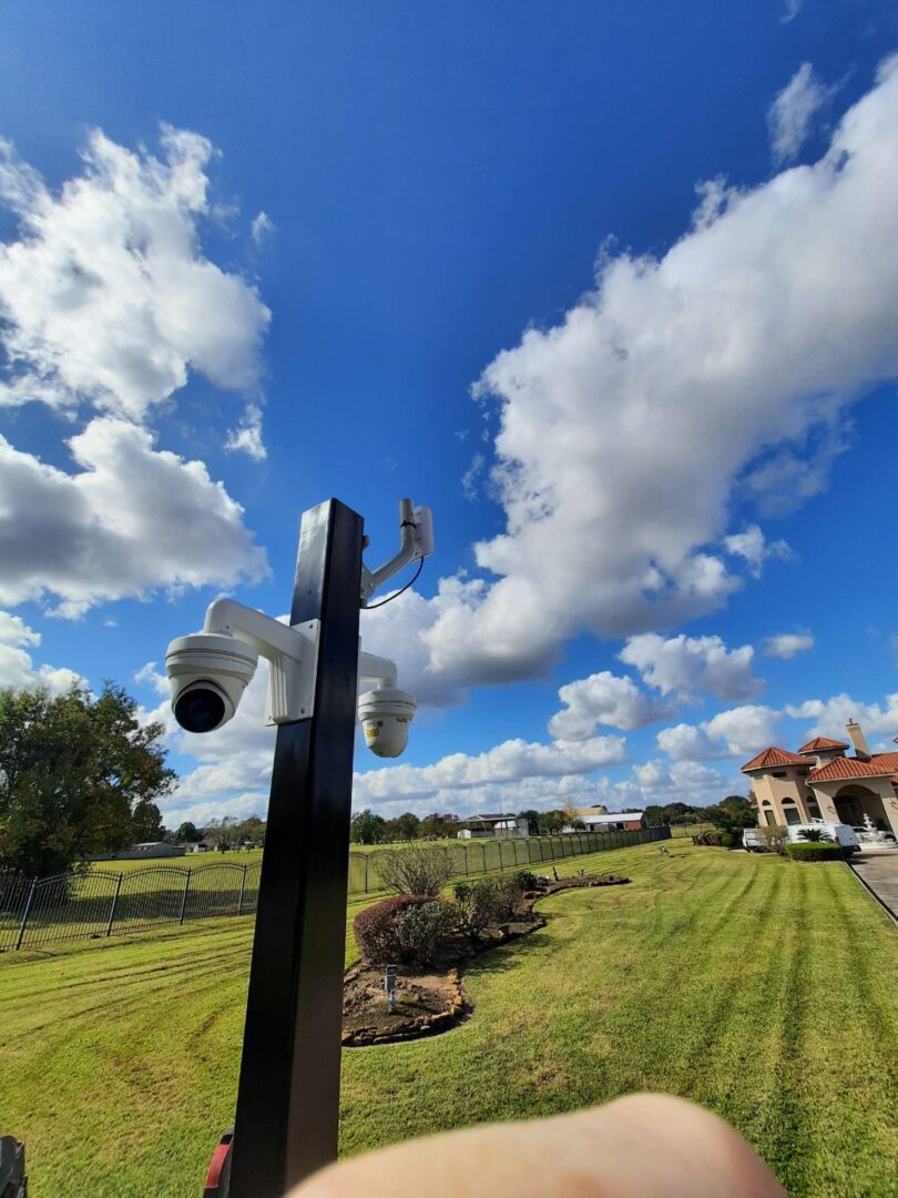A camera on top of a pole in the middle of a field.