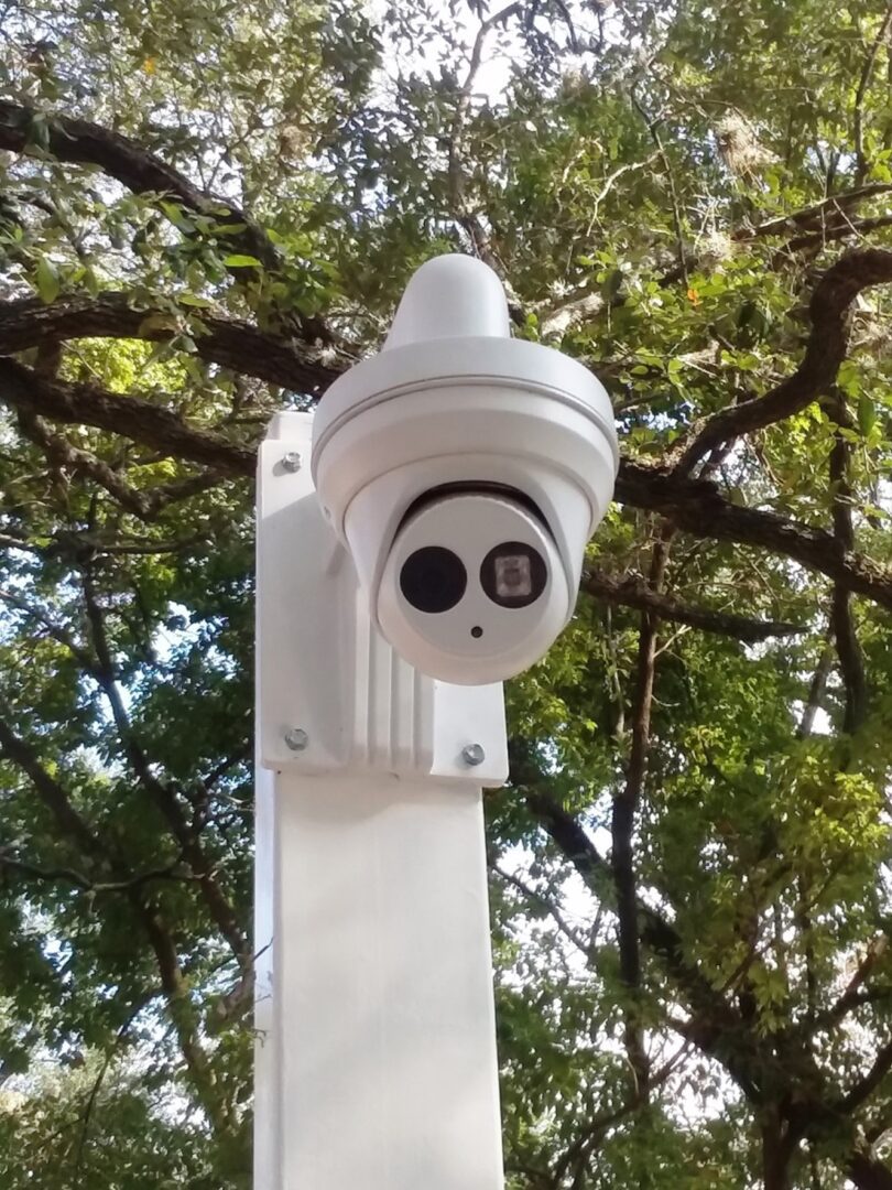 A white camera mounted to the side of a pole.