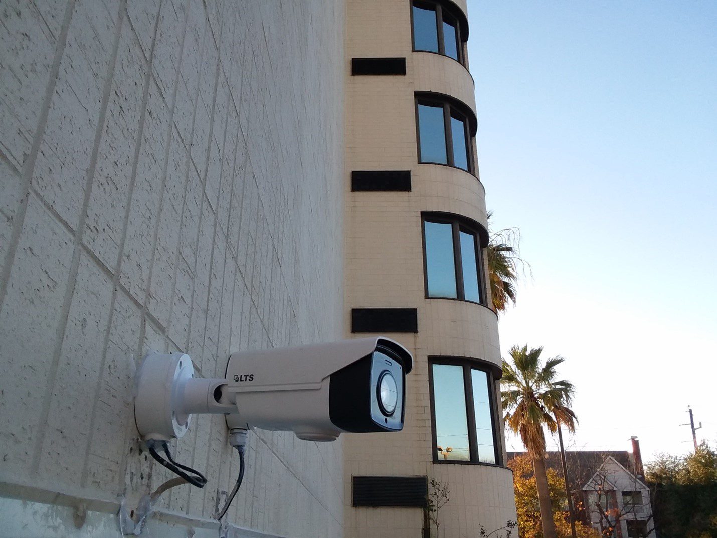A white camera mounted to the side of a building.