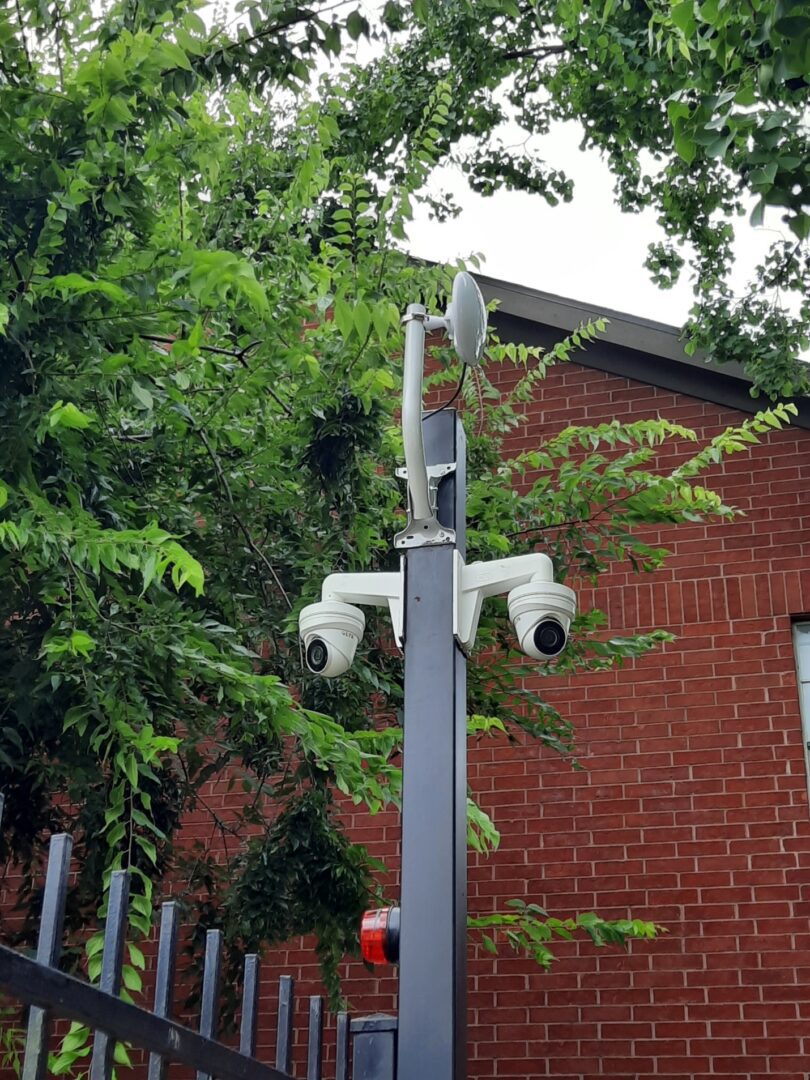 A pole with two cameras on it next to a building.